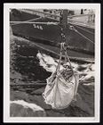Man in canvas bag over water between ships 